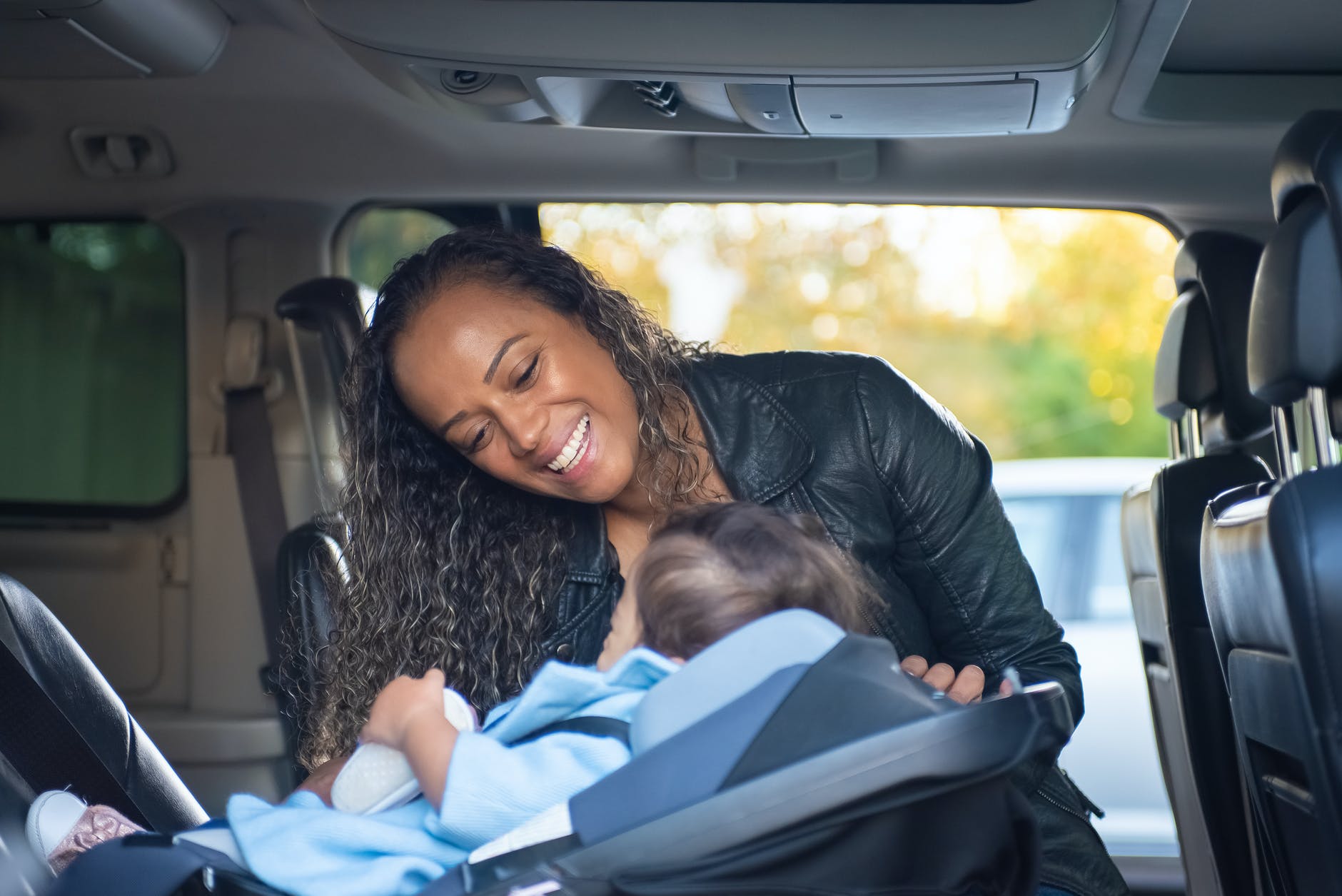 a woman looking at her child on a car seat